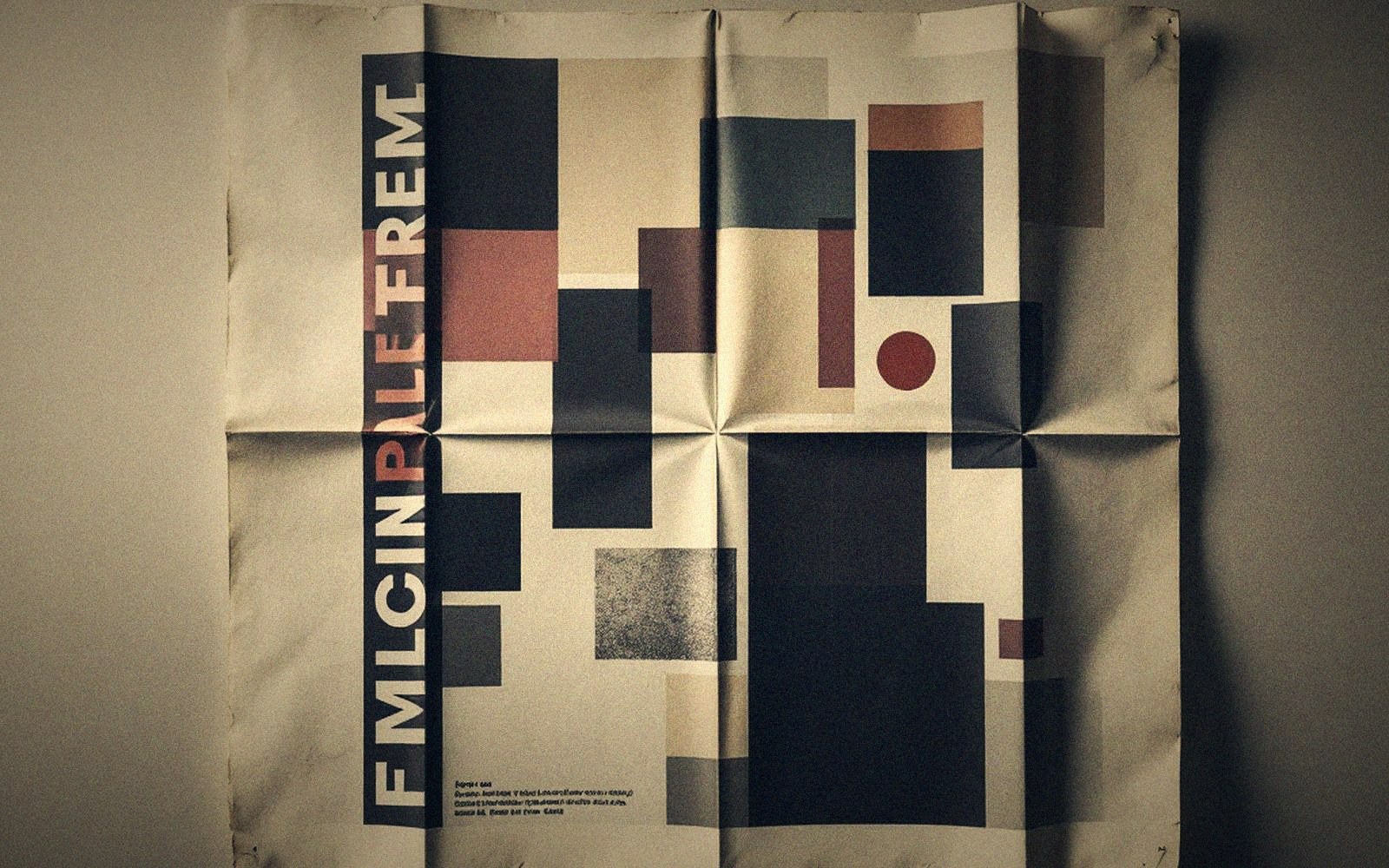 A creased poster with geometric blocks in muted red, navy and beige tones, pinned to a wall