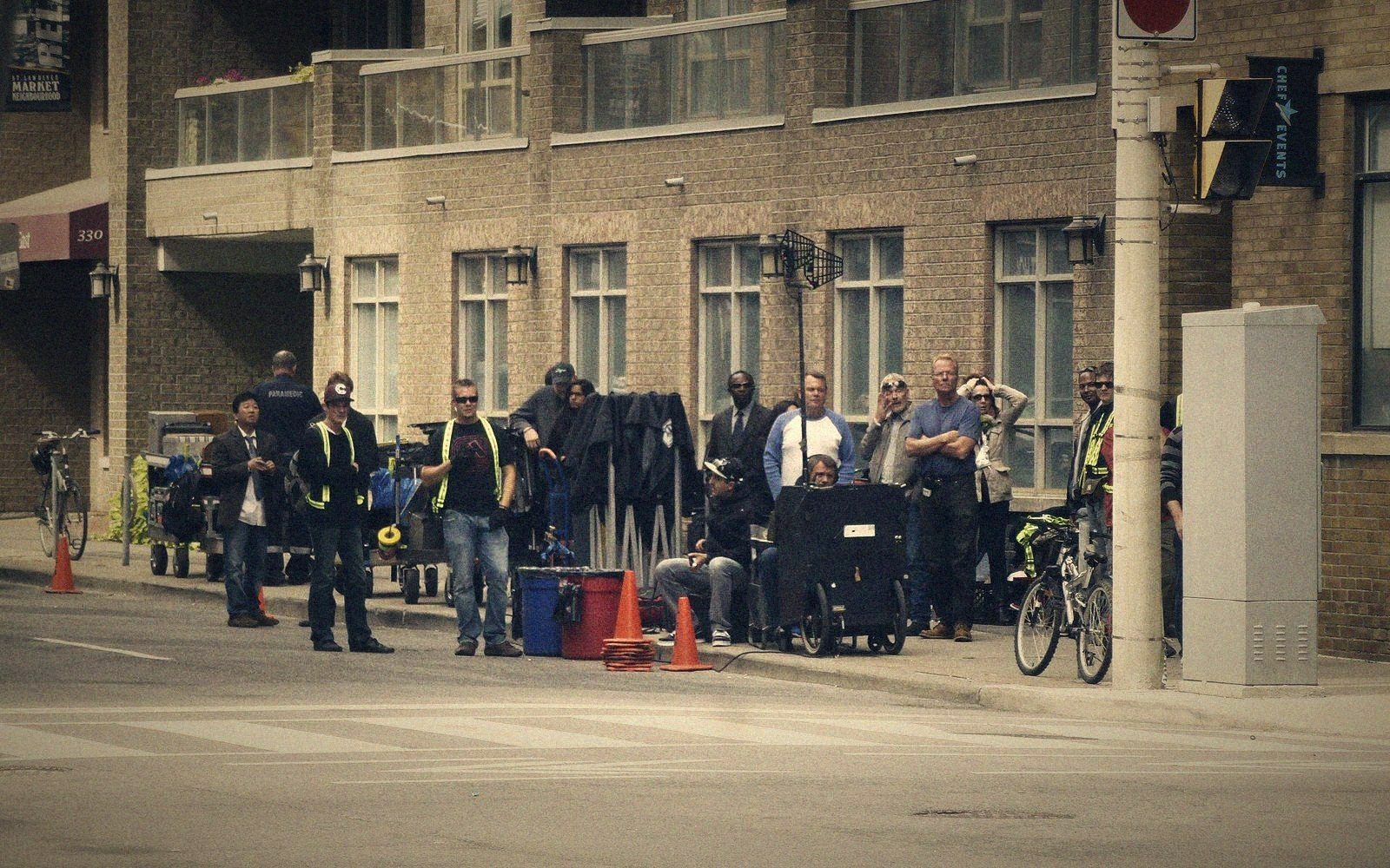 Film crew and equipment carts gathered along a city sidewalk during a shoot